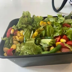 Packed and ready for your healthy lunch break. This fresh salad with lettuce, corn, and tomatoes is a convenient and delicious way to stick to your diet goals.