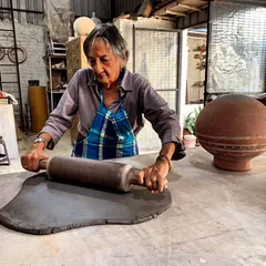 There is no age for learning. This student is rolling out a large slab of dark clay with focus and power, proving that creativity is timeless.
