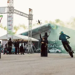 Another angle of the stunt show, capturing a rider mid-wheelie with a drone flying overhead. We use dynamic media coverage to capture every angle of the action.