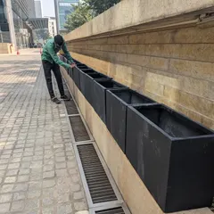 The empty planters are placed in their designated spots along a stone wall, ready to be filled with soil and plants.
