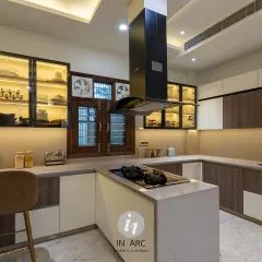 This angle highlights the U-shaped counter layout, providing ample workspace. The combination of wood-grain and white laminates with glass-front upper cabinets creates a balanced, modern look.
