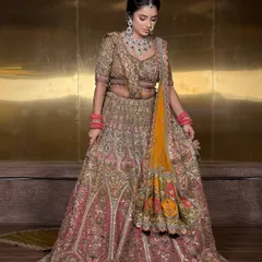 A full-length view of a heavily embroidered bridal lehenga. The dupatta is pleated and pinned securely at the shoulder to keep it in place while showcasing its beautiful border.