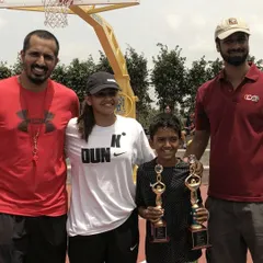 A throwback to our early days on an outdoor court. A young player proudly holds his trophies, a reminder of how far we've come.