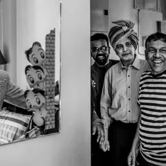 A joyful, candid moment in black and white. The groom looks at his reflection while his smiling father and friends look on, sharing in his happiness.