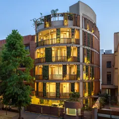 The Outré House in New Delhi, where handcrafted details and natural elements intertwine. The curved facade features a unique combination of precisely turned wooden louvres and vertical green walls, creating a living, breathing skin for the building.