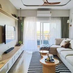 A full view of this modern living room, showing the connection to the balcony. We used a black and white striped rug to ground the space and sheer curtains to maximize natural light while maintaining privacy.