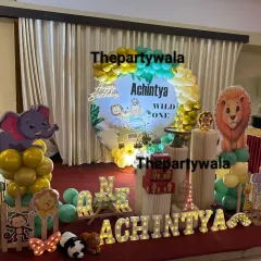 A 'Wild One' jungle theme for a first birthday. This stage setup features a large balloon arch, light-up letters, and plenty of cute animal friends.