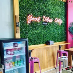 A simple boxwood green wall can completely change the vibe of a commercial space. Here, it serves as a vibrant backdrop for a neon sign in a cafe, creating an instantly Instagrammable spot for customers.