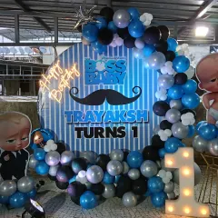 Who's the boss? This Boss Baby theme is perfect for a first birthday. It features a circular backdrop with character cutouts, a blue, black, and silver balloon garland, and a light-up number "1".