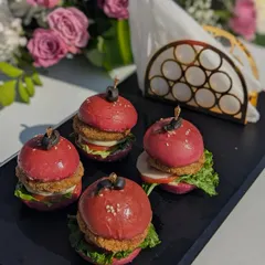 My mini burgers are a party favorite, featuring vibrant beetroot buns, savory patties, and fresh toppings. They are served on a sleek black platter, making them a visually striking and delicious addition to any appetizer menu.