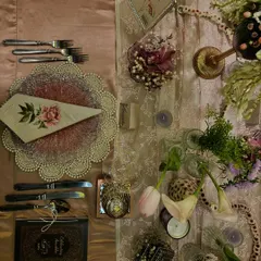 A flat lay of the place setting from Anushka Sharma's birthday dinner. It showcases the custom menu, the delicate floral napkin, and the layered chargers that contributed to the evening's elegant and personal feel.