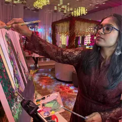 Deep in focus during a live painting session. You can see the grand wedding mandap in the background, which I am translating onto the canvas while the event unfolds around me.