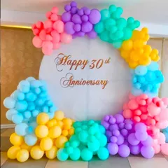 A colorful balloon decoration for a 30th anniversary. The pastel rainbow balloon arch creates a cheerful and celebratory backdrop.