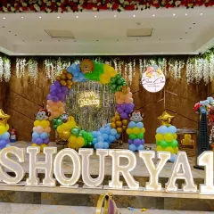 We transformed this venue into a jungle safari for a first birthday party. The setup includes a large balloon ring, monkey-themed balloon pillars, and large marquee letters for the birthday boy's name, creating a perfect photo backdrop.