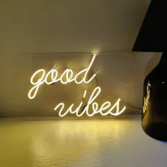 A classic "good vibes" neon sign in warm white. These signs are available to rent or purchase and can be customized to fit the theme and color scheme of your event.