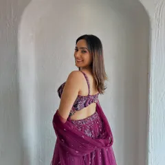 A smiling shot showcasing the back of the stylish velvet blouse. The tassel details add a playful touch to this elegant lehenga.