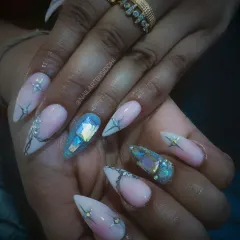 Sharp stiletto nails featuring a mix of delicate line work and bold, chunky iridescent crystals for a showstopping effect.