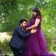 A classic couples maternity portrait with the partner gently kissing the baby bump. This outdoor shot in a beautiful purple gown captures the love and anticipation of expecting parents.