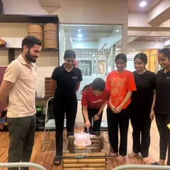 A moment of celebration as a member cuts her cake, surrounded by her fitness friends and trainers.