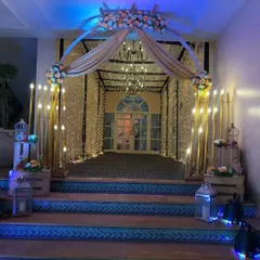 A rustic and romantic entrance design. We combined a fairy light tunnel with warm candle-like lights, wooden crates, and floral arrangements to create a charming welcome for the guests.