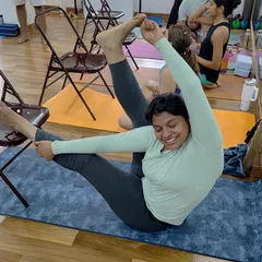 The joy of progress. This student is smiling through a challenging hip opener, showing that the journey is just as important as the final pose.