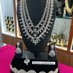 A complete bridal AD set, featuring a multi-layered haram, choker, hip belt, and maang tikka. This set with green stones provides a grand and cohesive look.