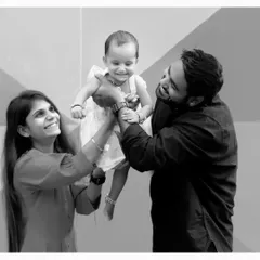 A joyful black and white family photo, with both parents lifting their baby up. These are the happy, candid moments that tell your family's story.