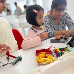 A young learner works with a LEGO WeDo kit, getting an early introduction to simple machines and programming concepts with guidance from an instructor.