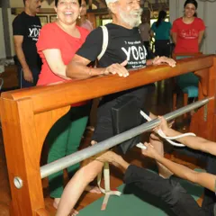 This student is being guided through a therapeutic sequence using a specialized prop to address spinal issues. This is not about temporary relief with pills. We use the Iyengar method to fix the root of the pain, allowing you to stand tall and move without wincing.
