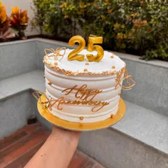 Celebrating a 25th anniversary with this elegant white and gold cake. It features a "25" candle topper, gold butterfly accents, and a "Happy Anniversary" sign.