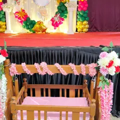 A close-up of the decorated wooden cradle for the christening ceremony, adorned with pink and white floral arrangements.
