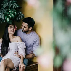 A sweet, candid moment on a bench, with the couple sharing a laugh. The natural framing and relaxed poses make this feel like a stolen, happy moment.