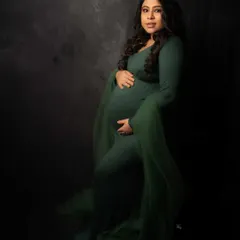 Strength and grace in one frame. This stunning mama-to-be wears a beautiful emerald green gown, her confidence glowing against the dark, textured backdrop.
