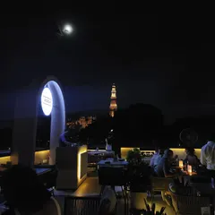As night falls, the terrace comes alive. The combination of our modern, illuminated bar, the moonlit sky, and the historic monument creates an atmosphere that is simply unmatched.