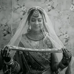 A classic black and white bridal portrait, with the bride gently holding her veil, creating a look of timeless elegance.