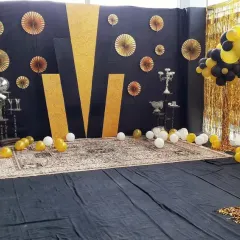 For smaller parties or corporate events, I can create custom photo booths or simple stage areas. This black and gold themed setup uses a patterned backdrop, balloon arrangements, and decorative props for a stylish selfie spot.