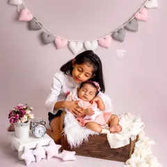 A sister's love is unconditional. This tender moment shows an older sister watching over her sleeping baby sibling, a memory to be treasured forever.
