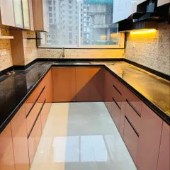 The U-shaped layout provides an uninterrupted workflow, with everything easily accessible. The glossy floors and cabinets reflect light from the large window, making the space feel bright.