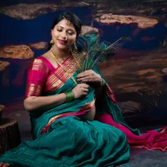 A serene moment captured in the studio, with a mother-to-be in a saree holding peacock feathers close to her bump.