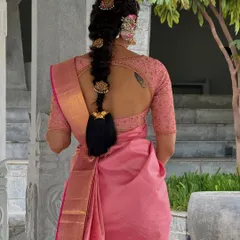 A back view of Shwetha Prasad's lotus pink ensemble, highlighting her traditional braided hairstyle and the keyhole back of the custom blouse.