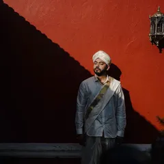 A powerful groom portrait against a bold red wall. The dramatic shadow and his contemplative expression create an artistic and memorable shot that showcases his personality.