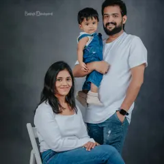 A classic family portrait with a casual, modern feel. The simple white shirts and jeans create a cohesive look that keeps the focus on their happy faces.