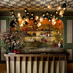 A custom installation of the Bocci 100 series flows over a bar, creating an immersive canopy of light. The interplay of dark and light pink glass forms provides a warm, ambient glow, demonstrating how I use clustered pendants to craft a unique atmosphere for commercial and hospitality environments.