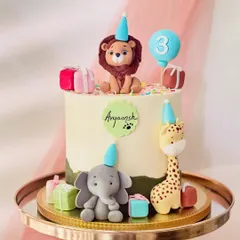 This jungle-themed cake for a third birthday features a lion, elephant, and giraffe in party hats. The design is personalized with the name 'Aryaansh' and a cute paw print.