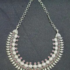 A premium pure silver necklace with a traditional flair. This crescent-shaped piece features repeating motifs studded with pink stones, creating an elegant collar-style necklace.