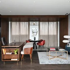 A wider view of the Chairman's office, showing how the main workspace flows into a comfortable lounge area. This multi-functional layout allows for both focused work and relaxed, informal discussions within a single, cohesive suite.