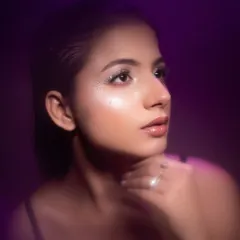 A purple light wash adds a touch of fantasy to this beauty shot. The model's upward gaze and the soft lighting create a hopeful and serene portrait.
