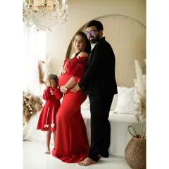 A beautiful family portrait celebrating the upcoming arrival. The mother's vibrant red dress stands out in our bright and airy studio.