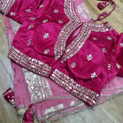 A closer look at a custom-stitched pink blouse with a keyhole back design. The intricate mirror work on the neckline and sleeves is designed to perfectly complement the client's saree for a wedding function.