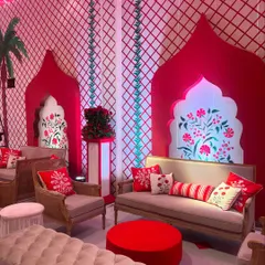 A cozy seating arrangement with a backdrop of red and white patterned walls featuring hand-painted floral motifs. The custom cushions continue the theme, ensuring every detail is perfectly coordinated.